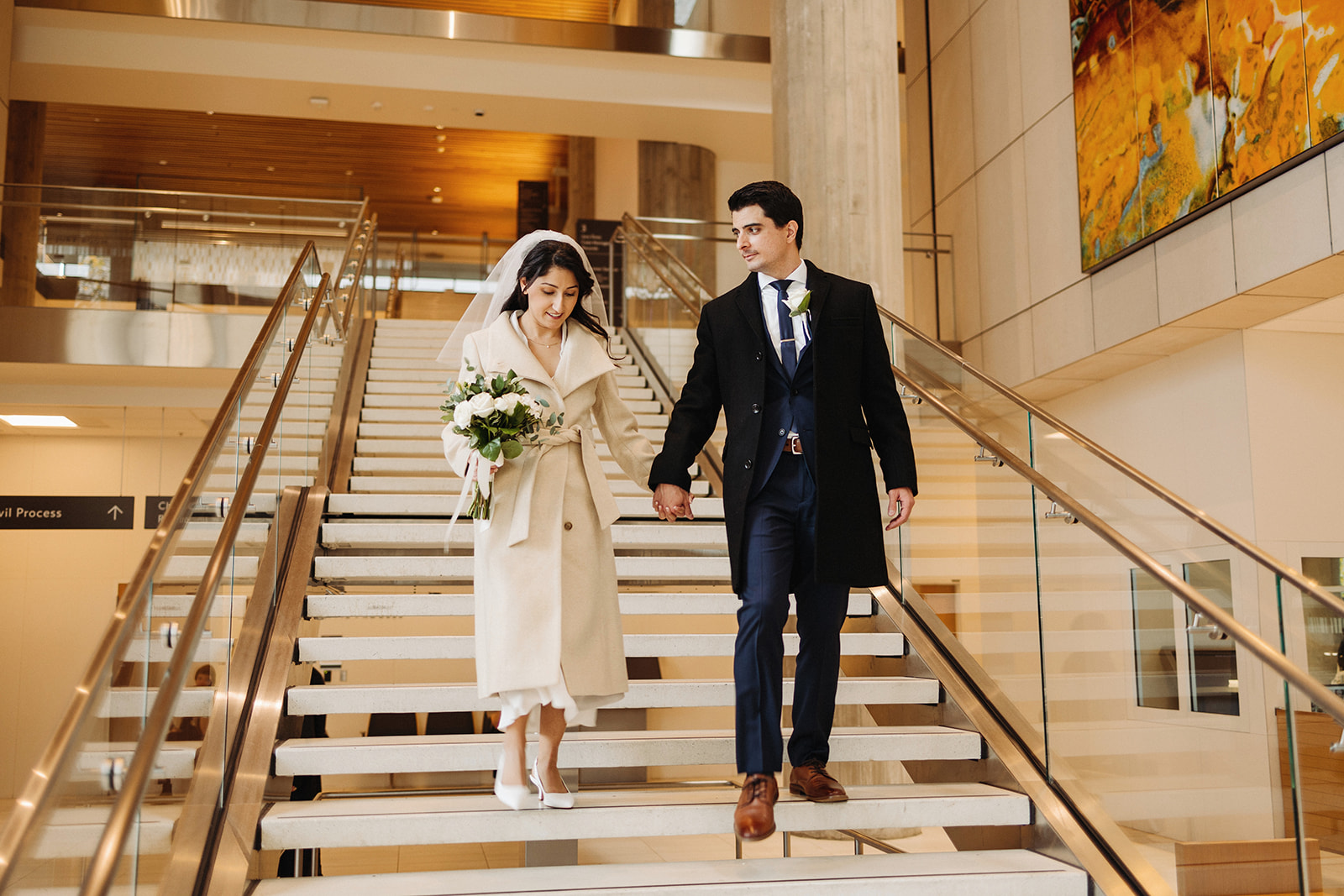 Bride and groom walking down the staircase at the new multnomah county courthouse in portland oregon